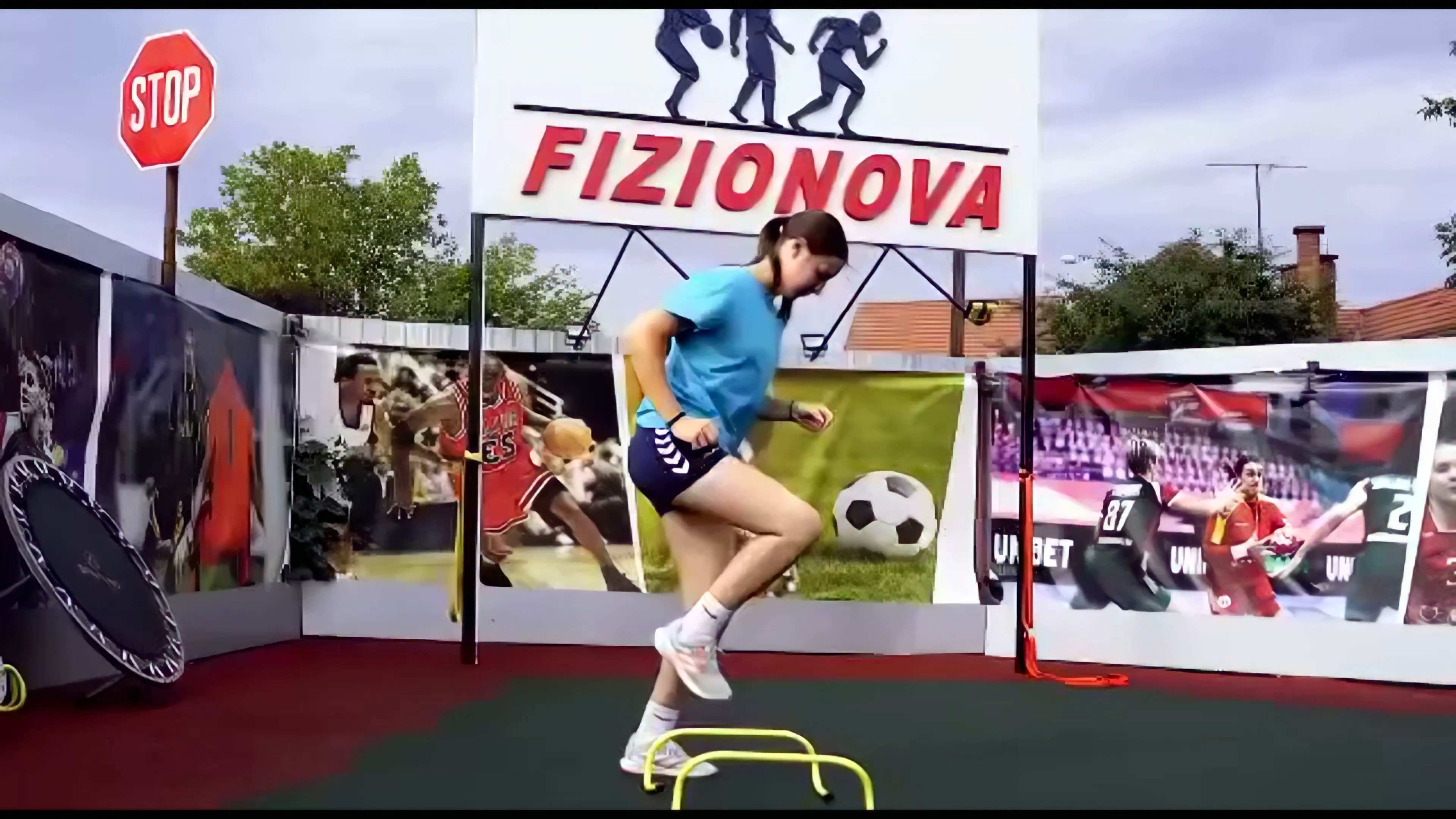 Sportivă executând un exercițiu de agilitate pe terenul exterior FIZIONOVA, cu obstacole și minitrambulină.